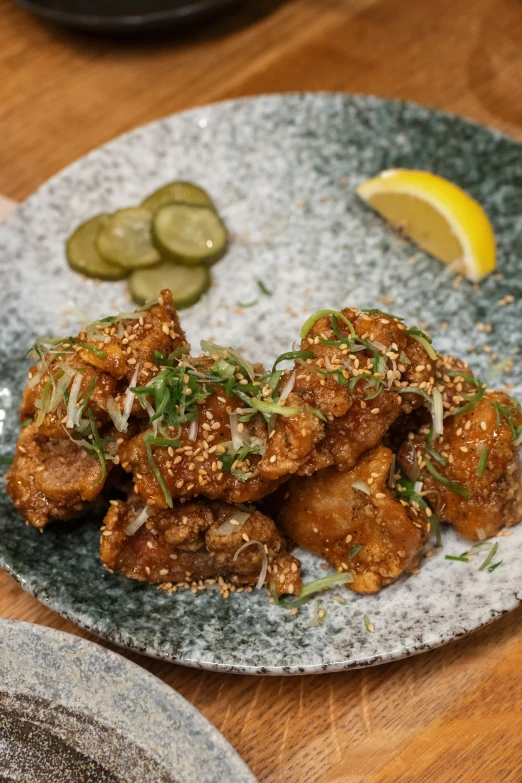 a plate of fried wings with pickles and breadcrumbs on a table