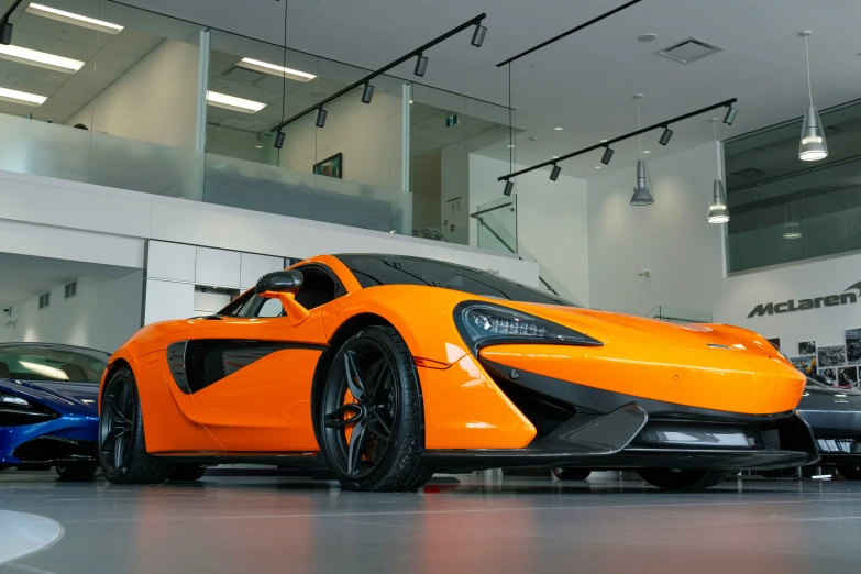 the very orange car is sitting in front of several other cars