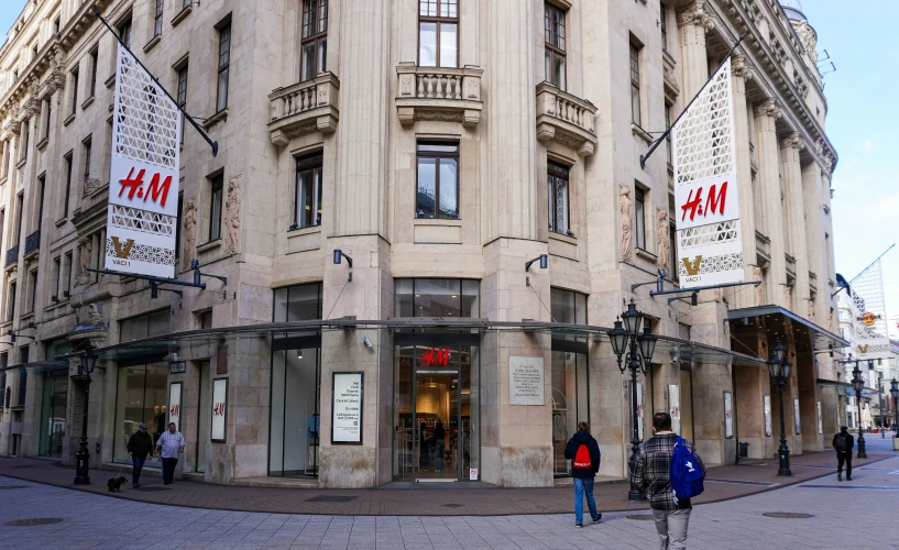 a large building with shops, pedestrians and traffic lights