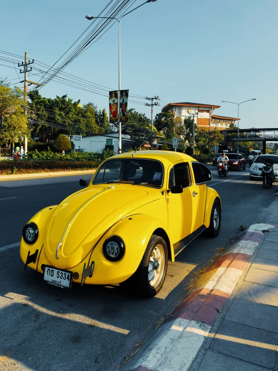 a yellow vintage car on street next to cars