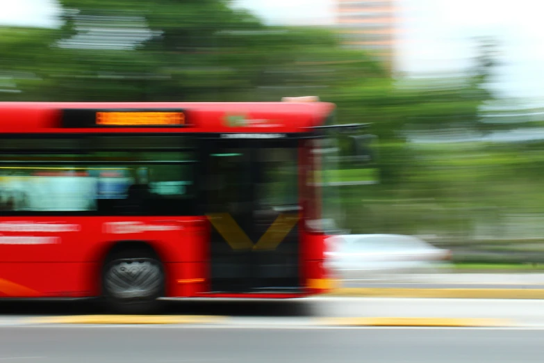 red bus driving down the road in front of some tall buildings