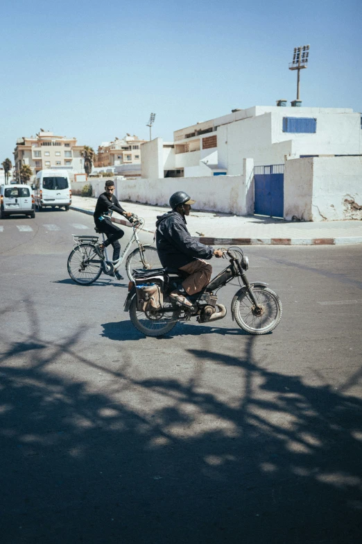 two motorcyclists passing a traffic light in the middle of a road