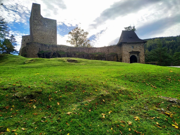 a stone building with a green field next to it