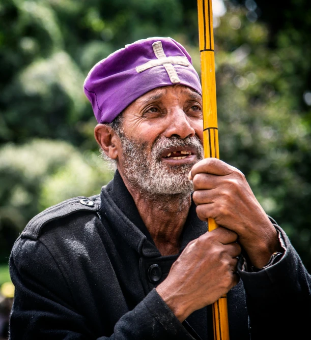 a man in a black jacket is holding a yellow pole