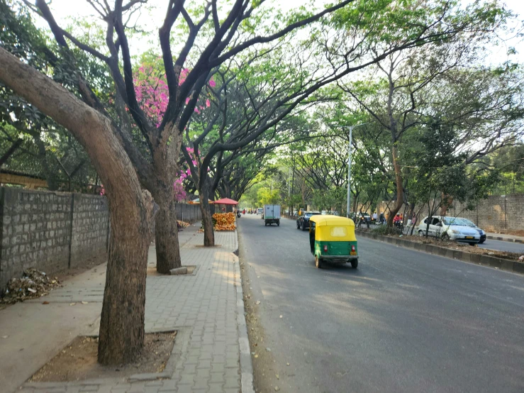 a yellow and green tuk traveling down a street