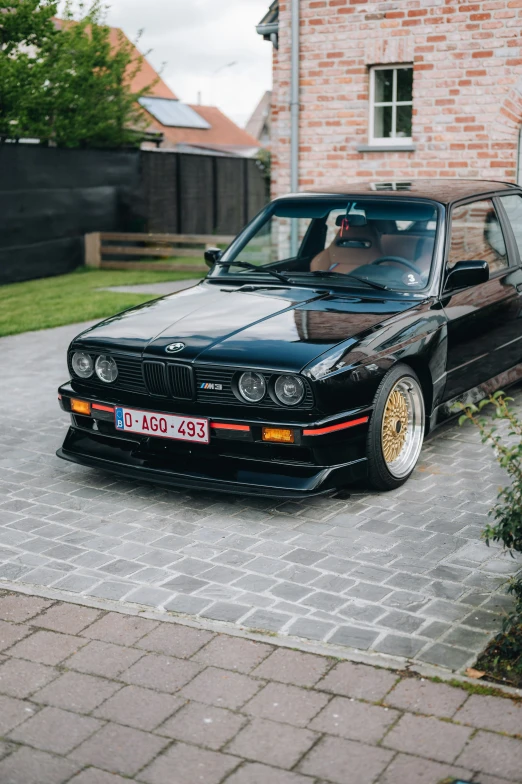 a black car with yellow ke rims parked outside