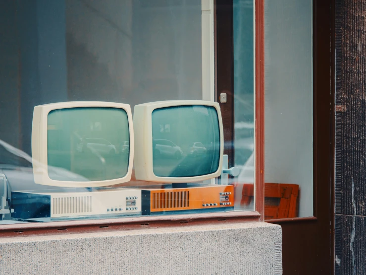 two old televisions are sitting in a window