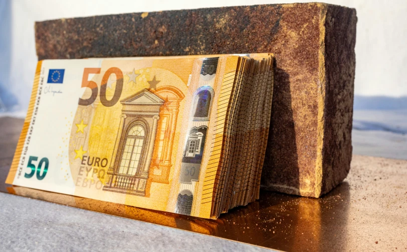 the new 50 euro bill is held up against the old wood