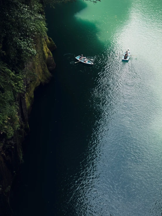 people in a small boat are cruising along a narrow waterway