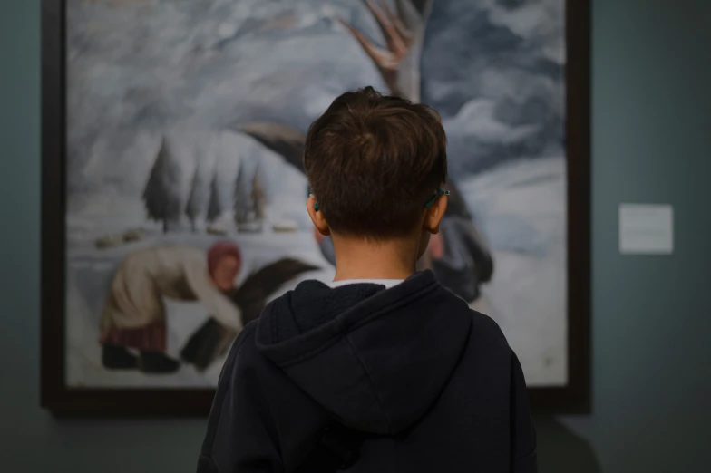 a little boy standing in front of a painting
