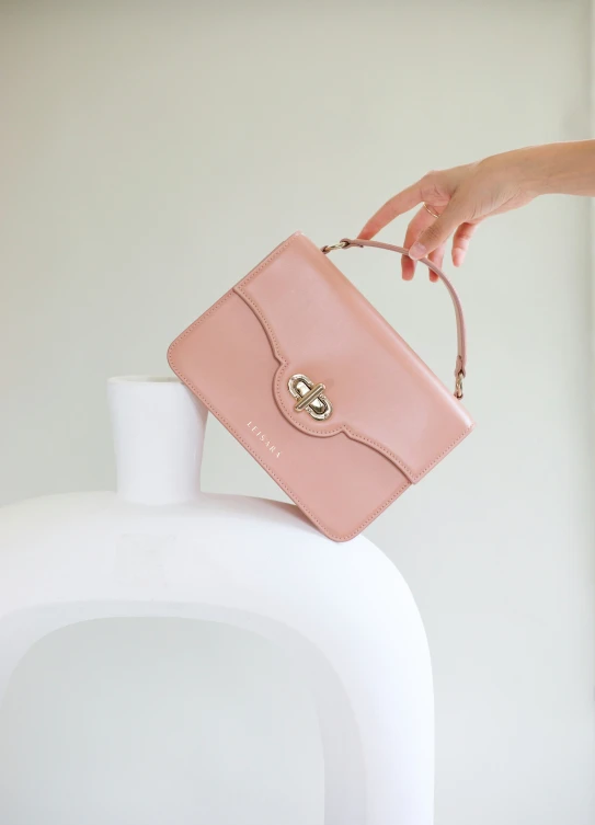 a person holding a pink purse above a white container