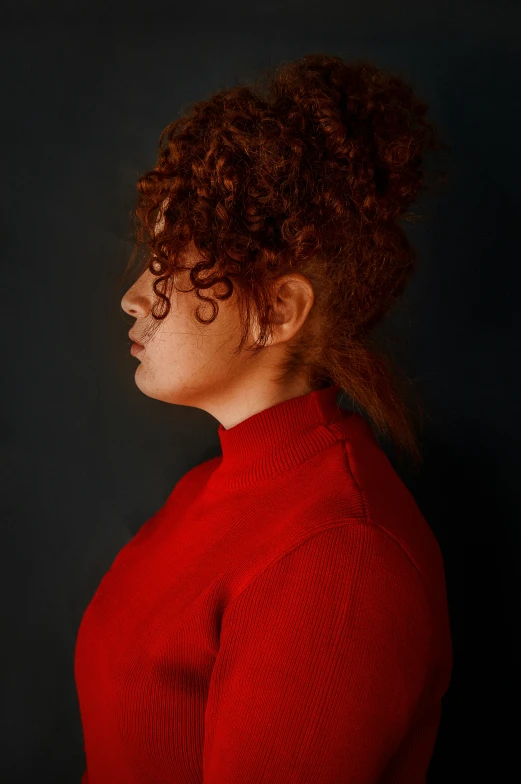 a black woman with curly hair standing with her head turned