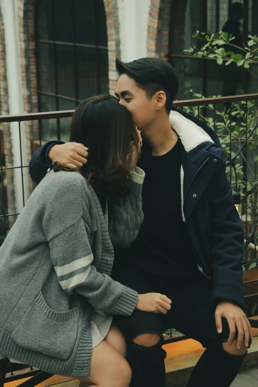 a couple sitting on a bench kissing while they are not kissing