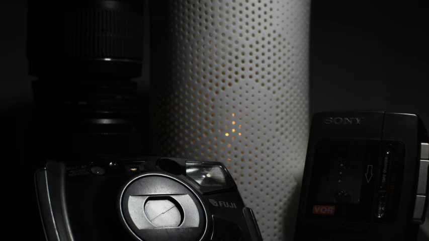 a black camera sitting next to a white vase