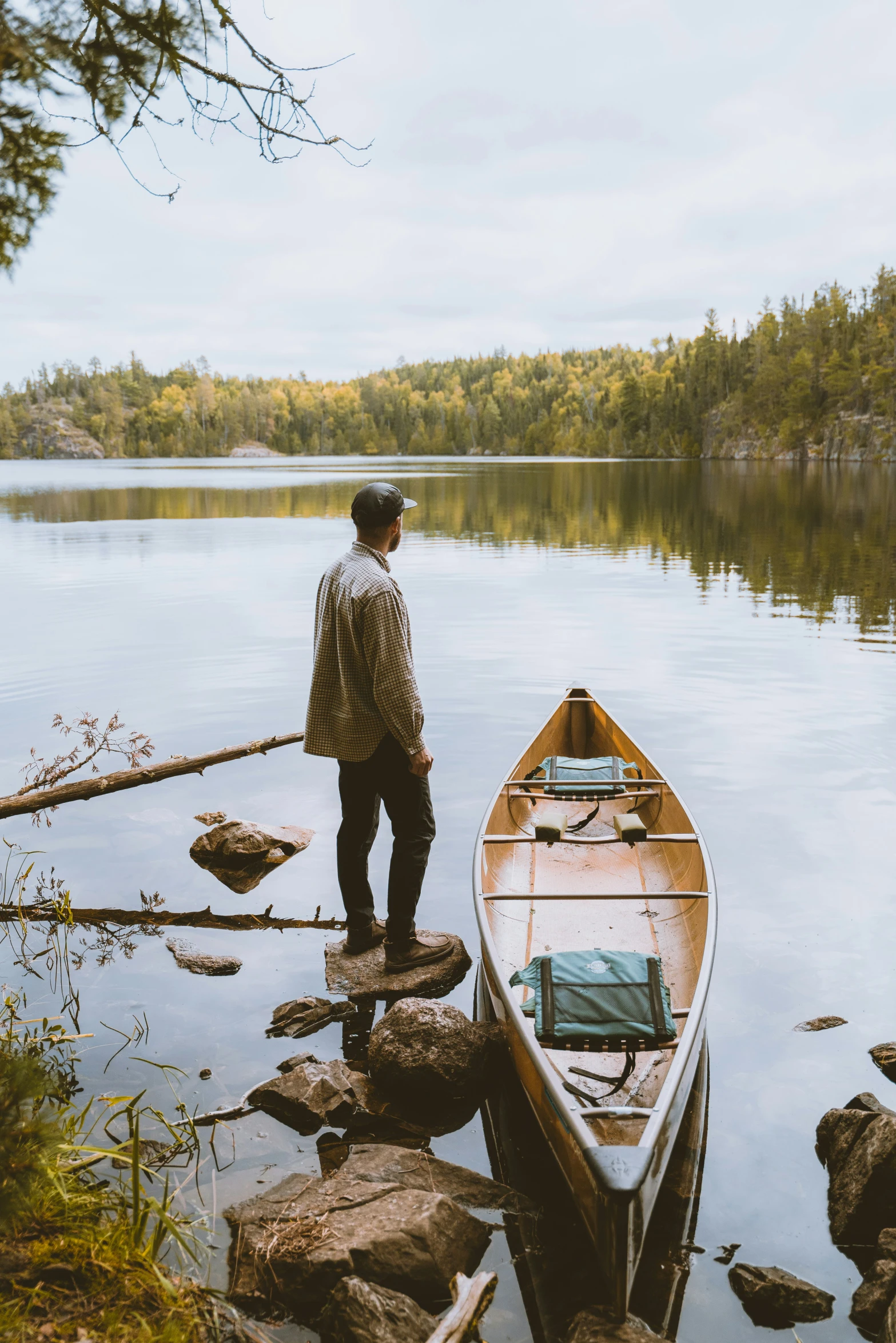 a man standing near the water next to a small boat