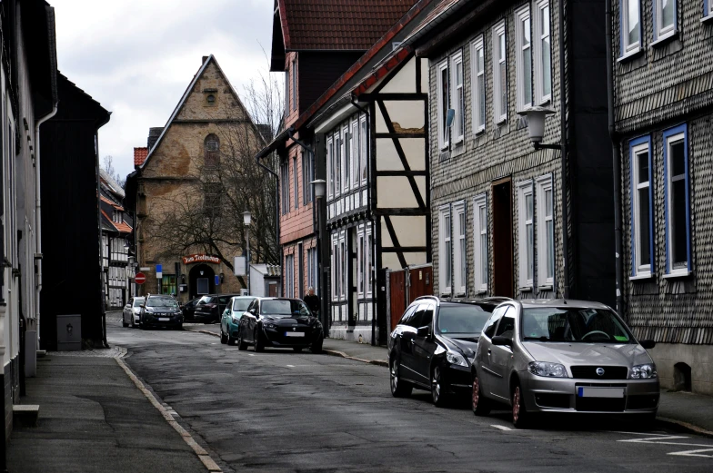 parked cars on a narrow city street with tall buildings