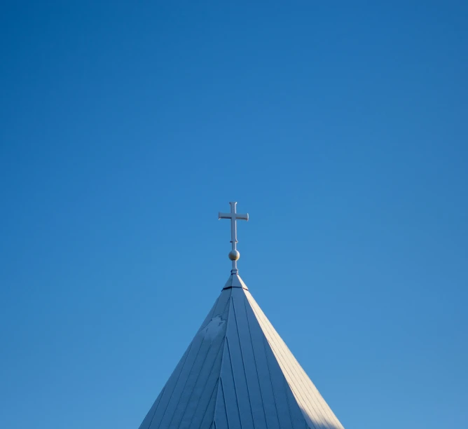 the cross on top of a church spire, a clear blue sky