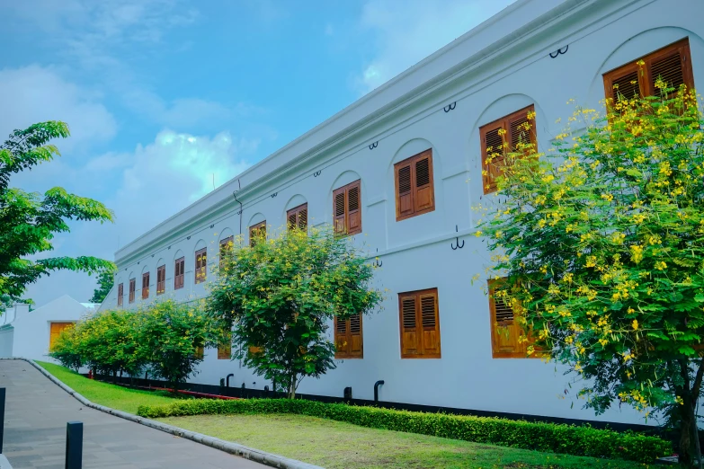 a building with many windows and a lush green park in front of it