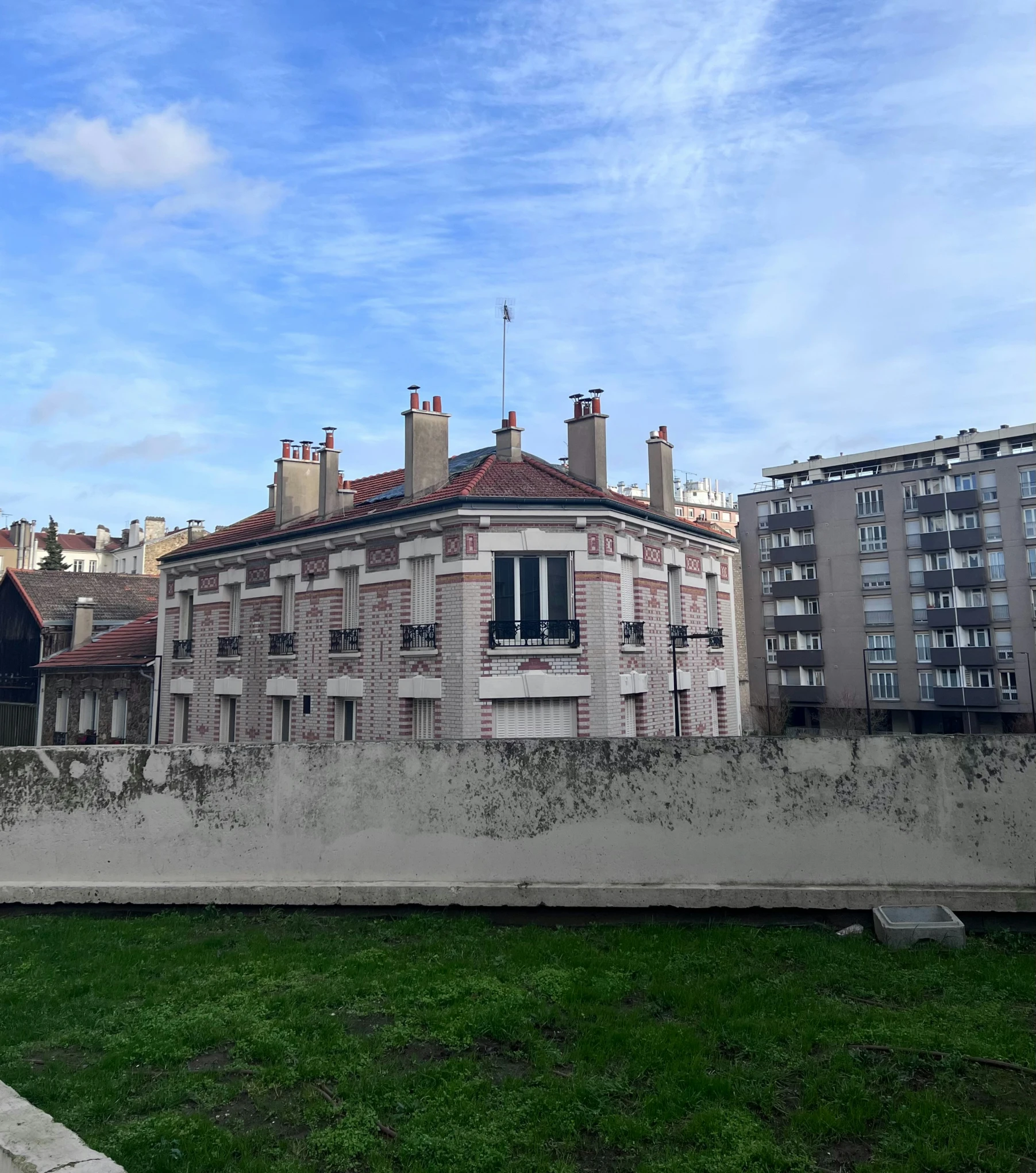 old buildings line the river bank near a green lawn