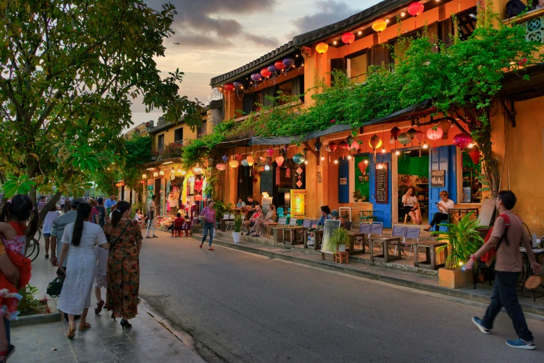 people walk along the street as a group of colorfully dressed people stand nearby