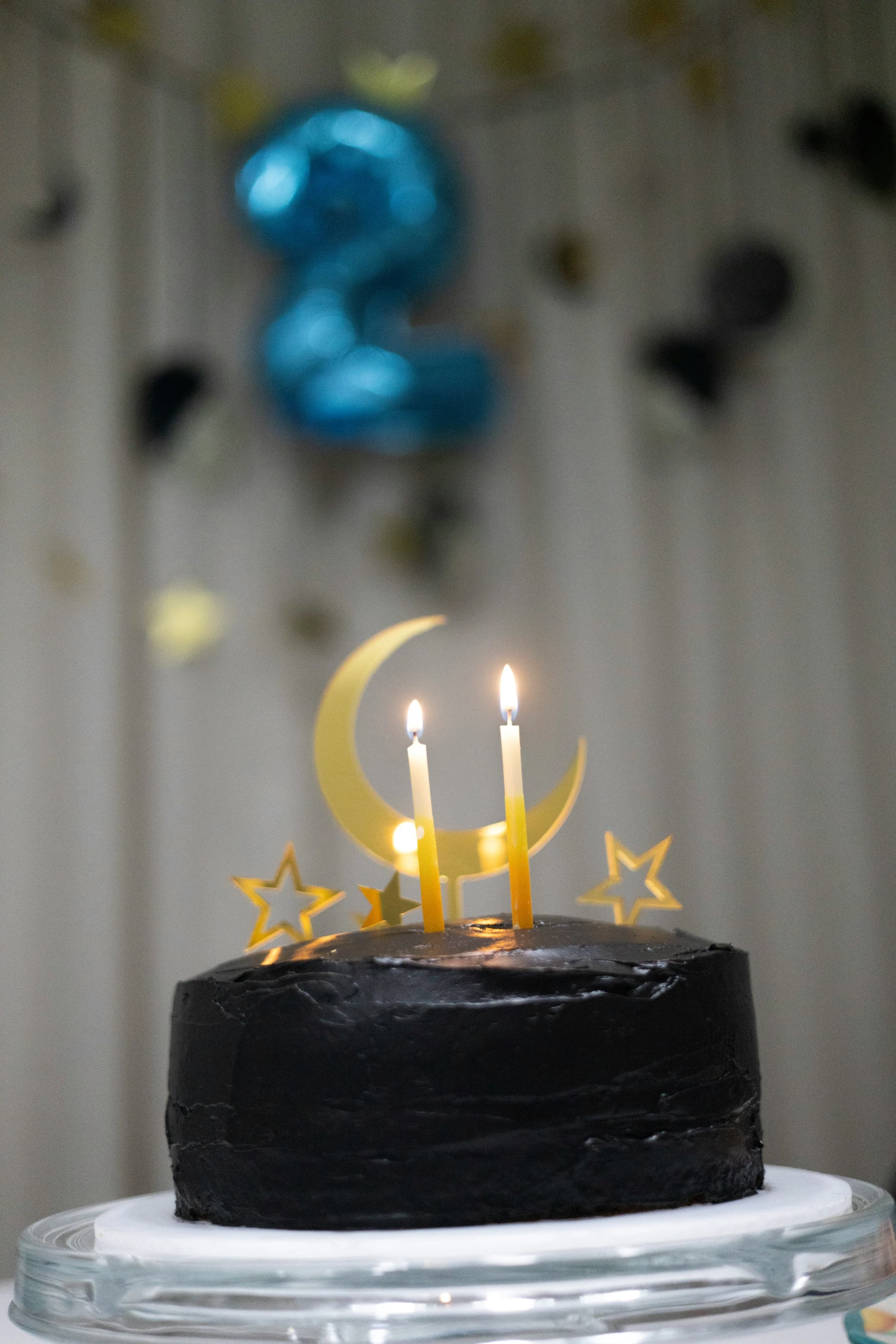 the black cake has two yellow candles and stars