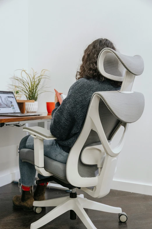 the back view of a person sitting in a white chair