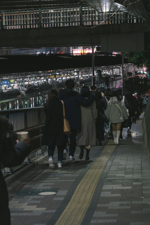 people walking along a walkway in the city at night