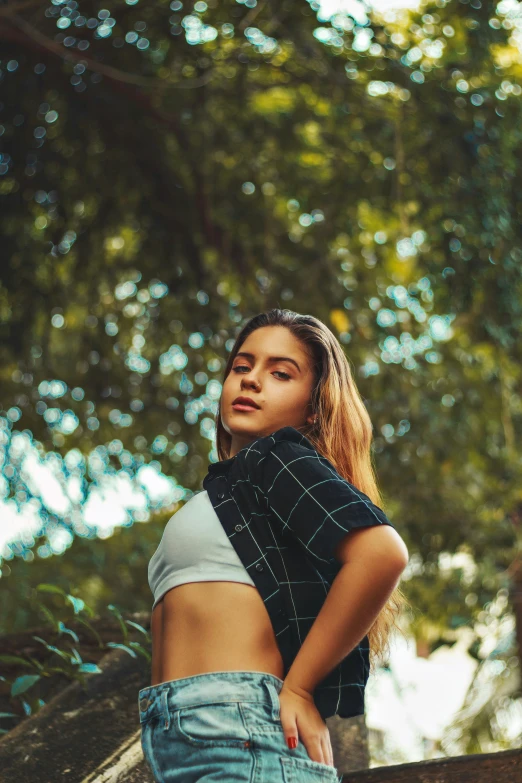 a woman standing on a tree nch with her legs crossed