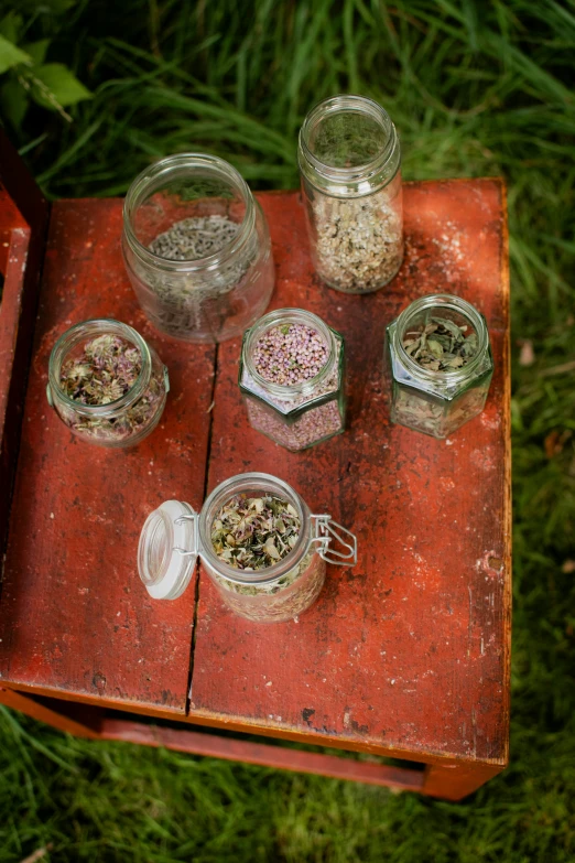 various containers of food and spices sitting on a small table in the grass