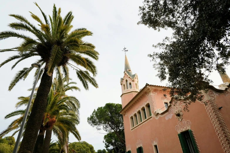 palm trees in front of a pink building with a clock