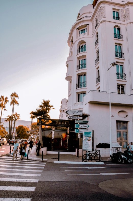 the view of a building from the street corner with pedestrians crossing