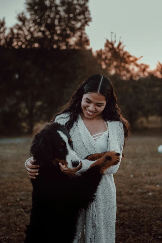 a woman is hugging a dog in the field