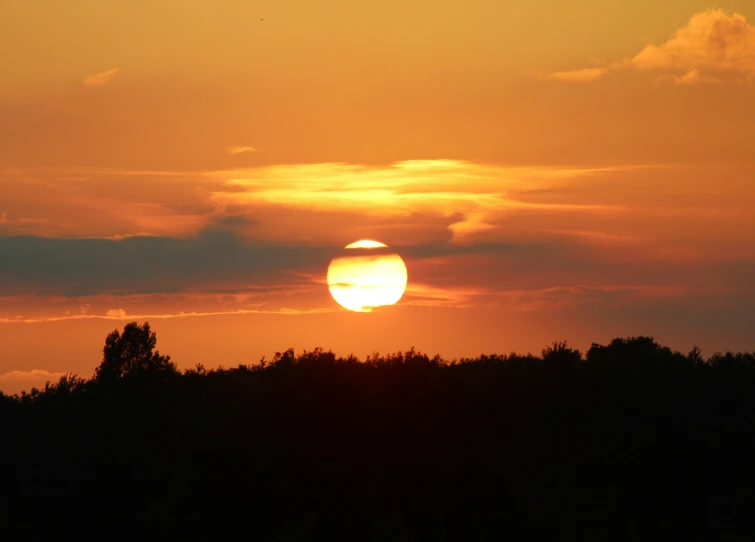 a large orange sun with some trees