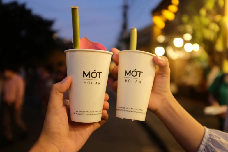 two people holding up coffee cups in front of a city street