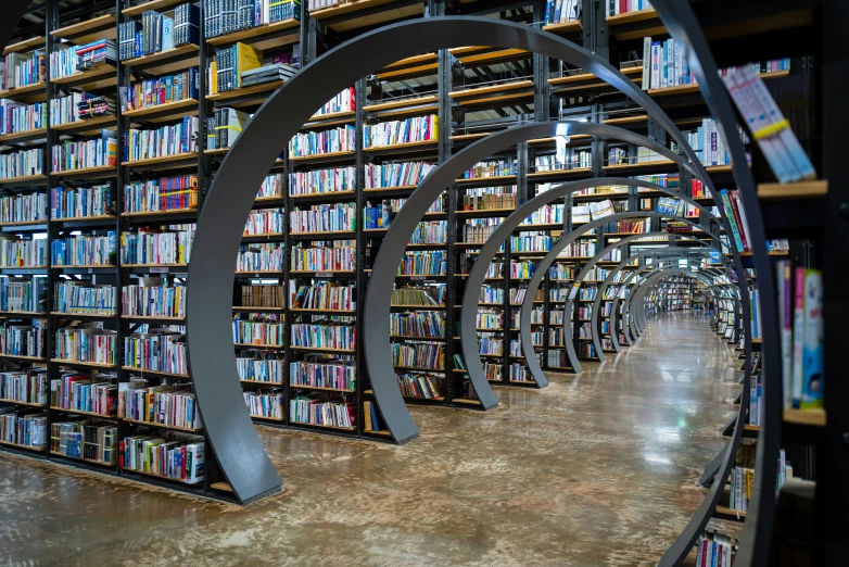 a circular circular iron sculpture sitting in the middle of a liry filled with books