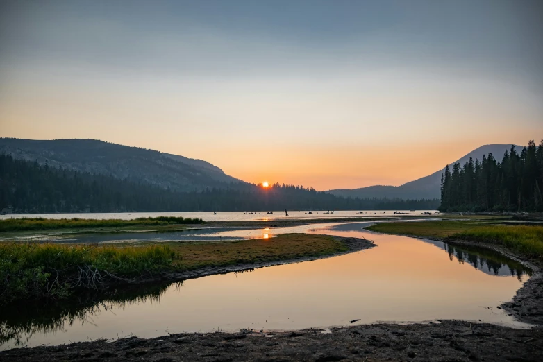 a sunset is reflected on the water in a lake