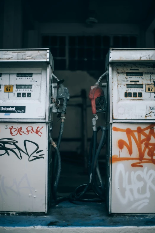 two public parking meters covered in graffiti and graffiti