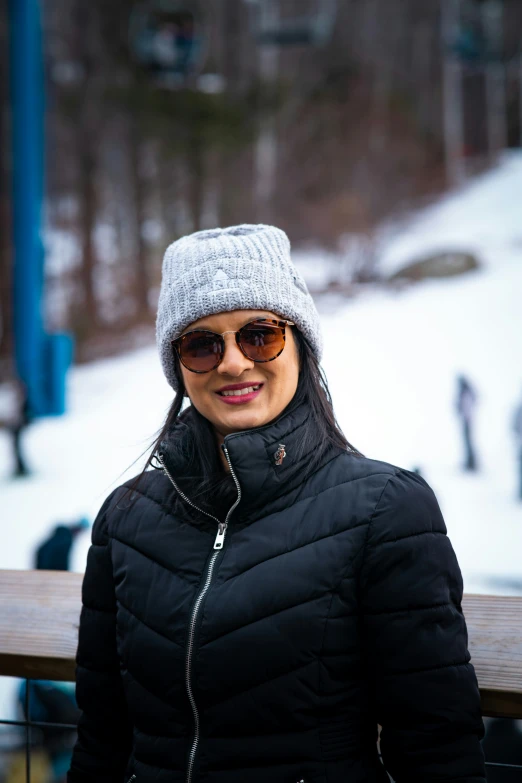 the lady is wearing a jacket and hat with sunglasses