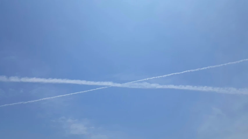 two jets flying through the blue sky leaving contrails behind