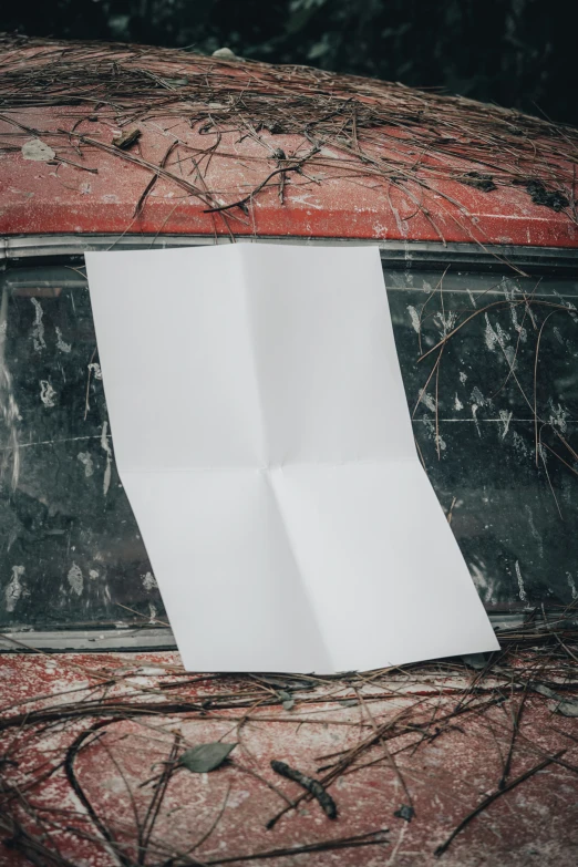 an old rusted and weathered red vehicle with a piece of paper attached to it