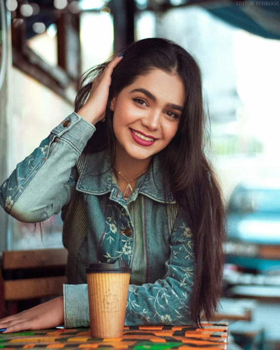 the girl is sitting at the table with a glass