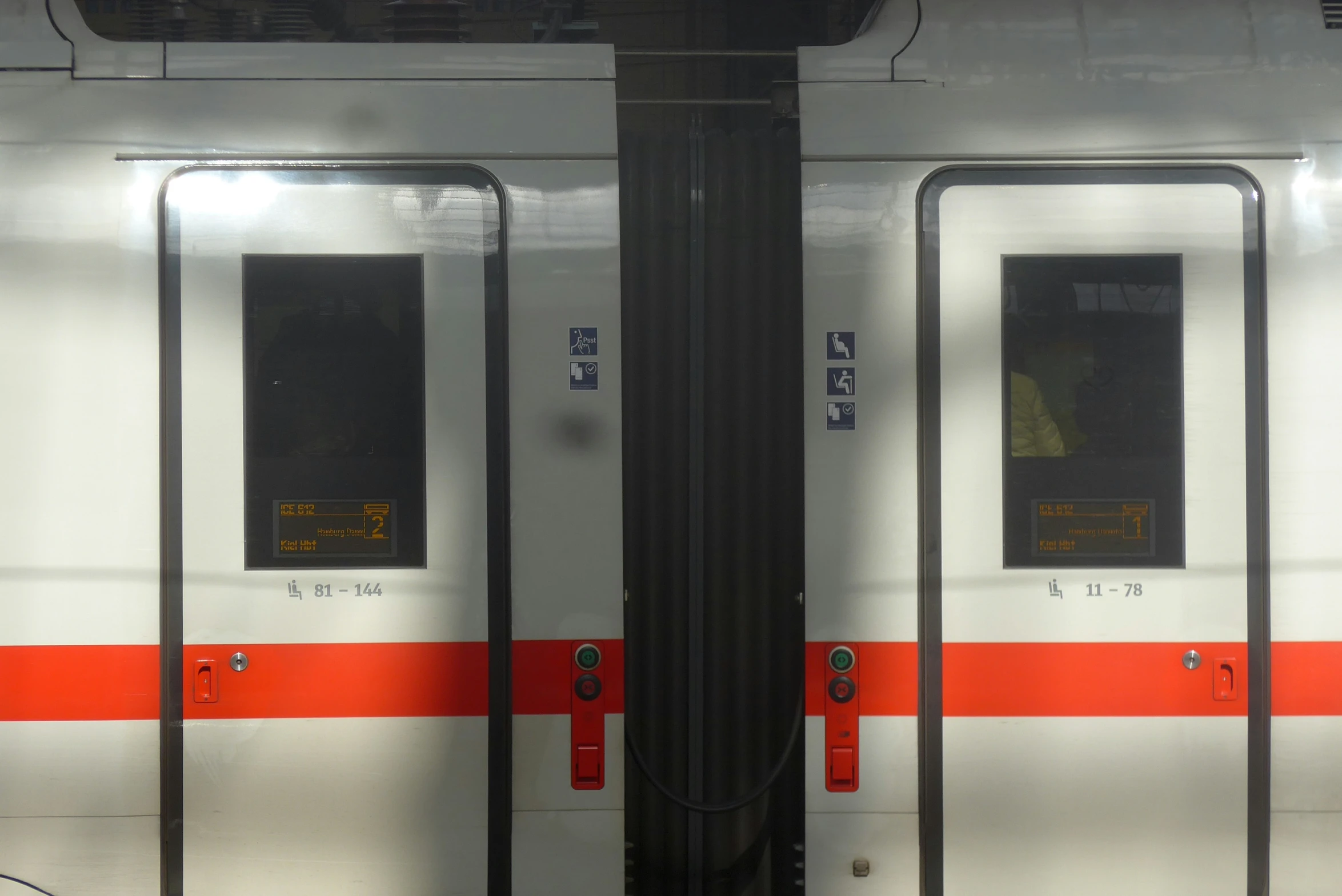 a train with an orange stripe on the side next to another one
