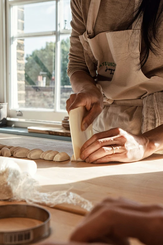 a person making bread and preparing soing on a wooden table