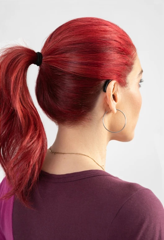 red hair is tied in a ponytail and with an earring in her left hand