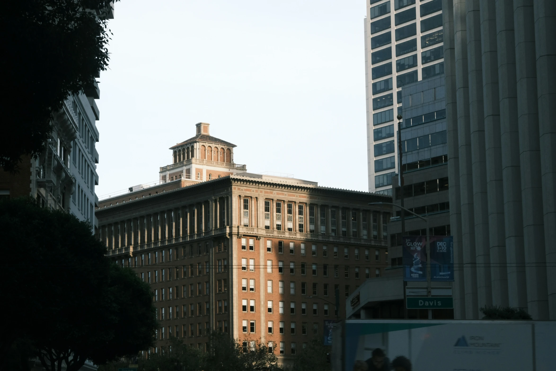 large brown building with a clock tower near skyscrs