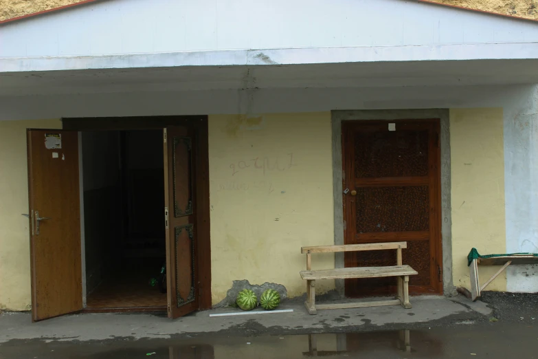 an entrance to a building with two doors and a bench