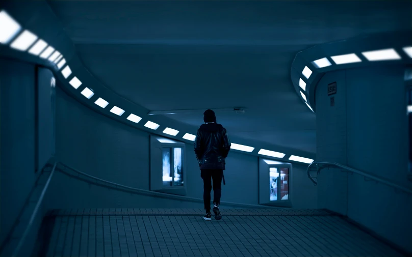 woman walking through tunnel towards exit in dark area