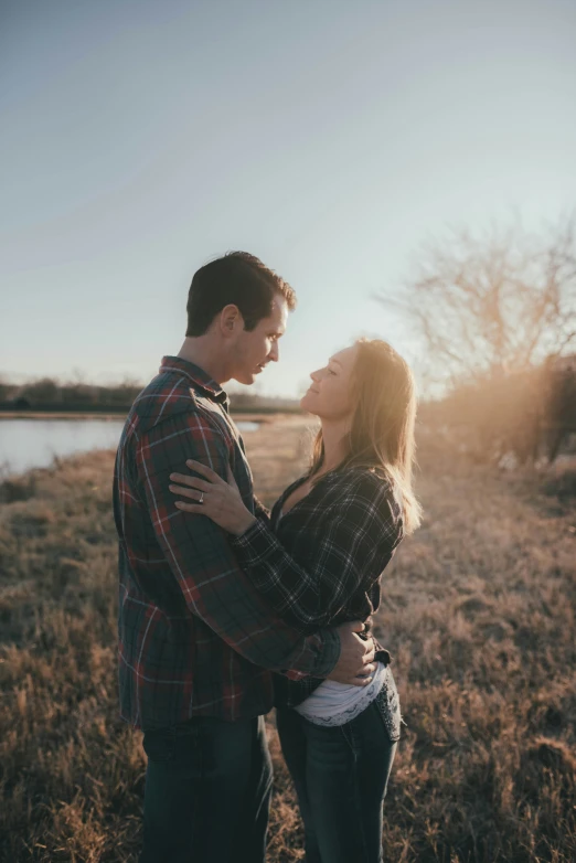 an engaged couple cuddling near the river in their natural po