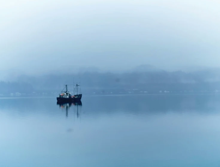 a boat floating on top of a lake covered in mist