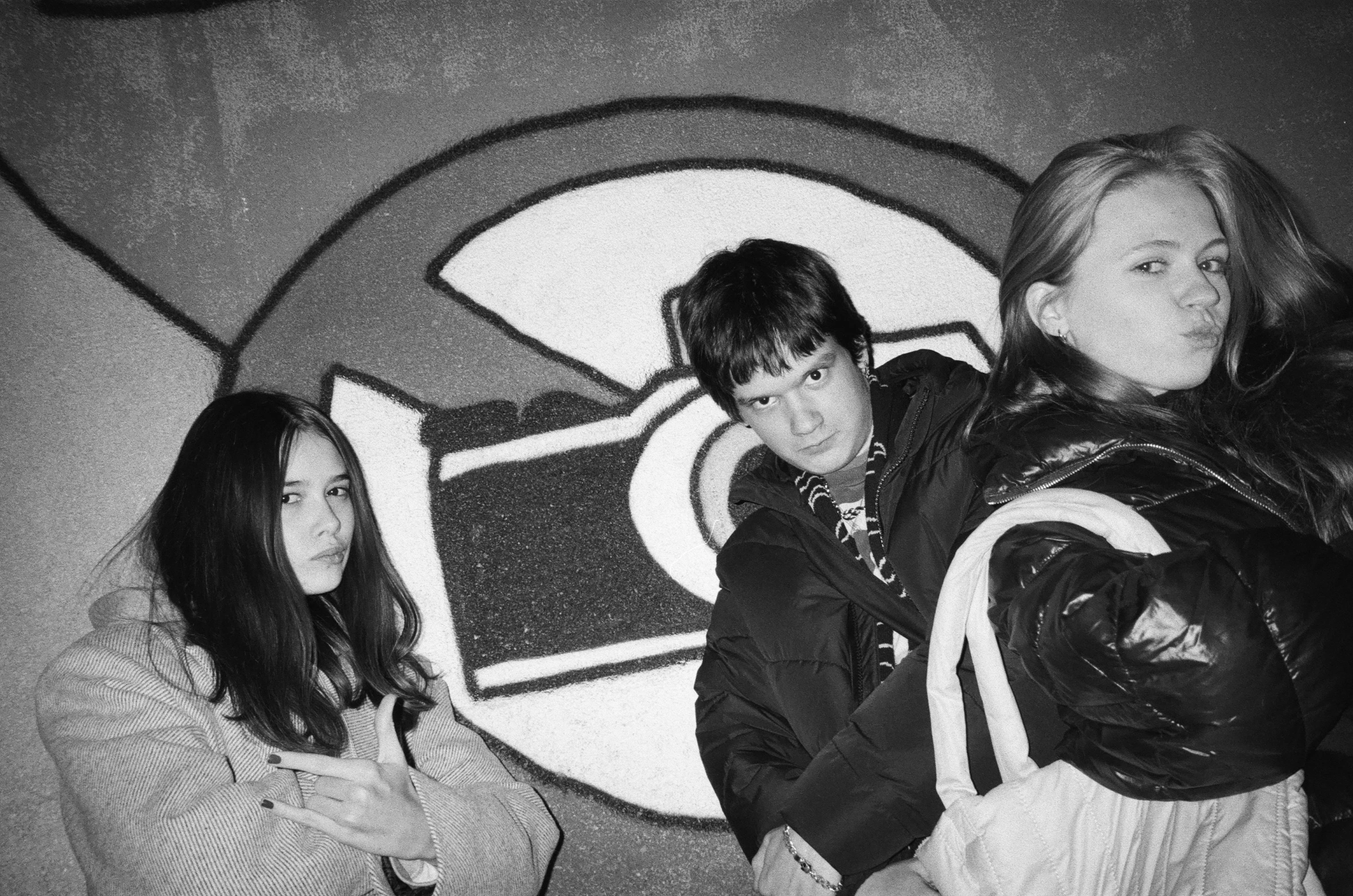 two girls and a boy holding bags pose for a po